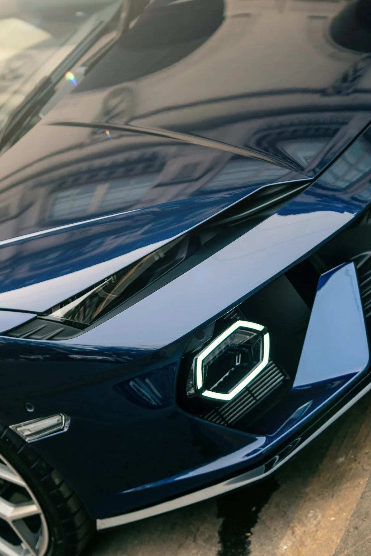 Close view of the polished navy bodywork and headlight of a sports car.